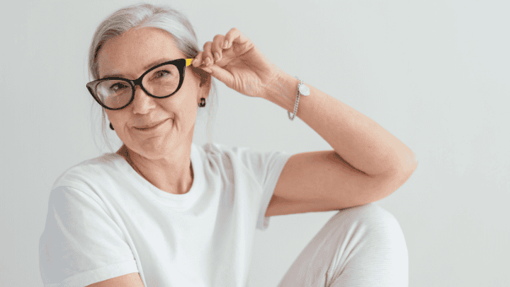 A Senior Lady Holding Up Her Glasses While Smiling